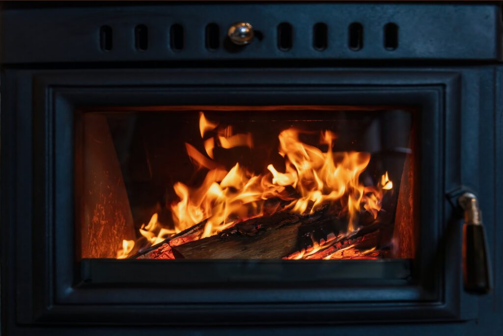 Burning fire in a wood stove fireplace radiates heat, warm home interior,