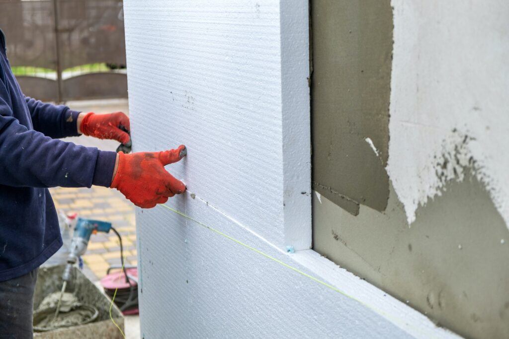 Construction worker installing styrofoam insulation sheets on house facade