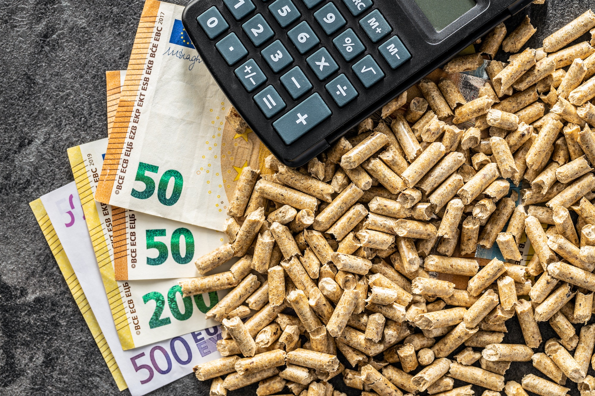 Wooden pellets, euro banknotes and calculator. Ecologic heating.