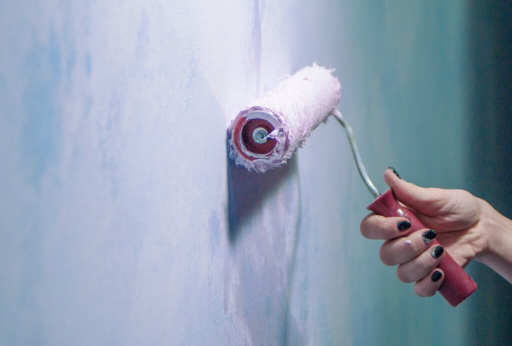 a young woman holds a painting tool for painting walls in pink