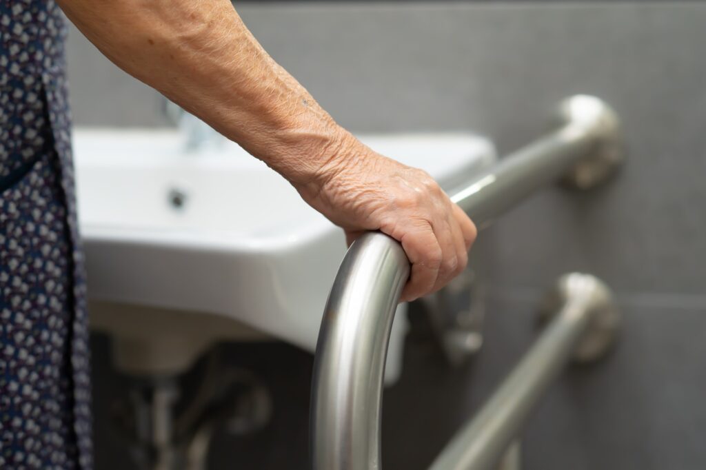 Asian elderly woman patient use toilet bathroom handle security in hospital.