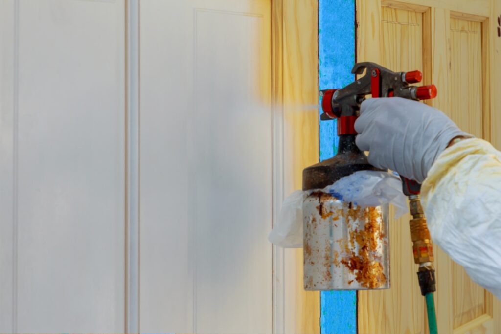 Hand with painting the door with a spray gun