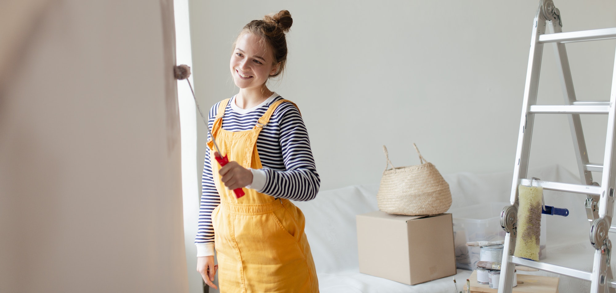 Happy young woman remaking her new flat, painting walls. Concept of renovation, indepent women and