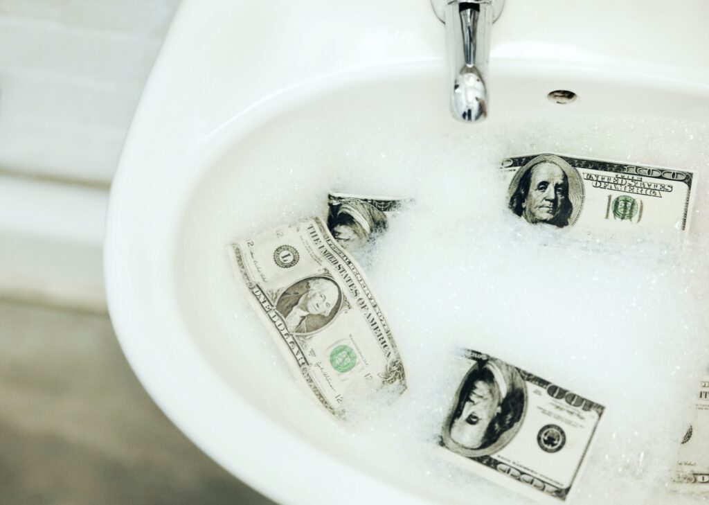 The art of money laundering. A sink with money that is soaking in foamy water.