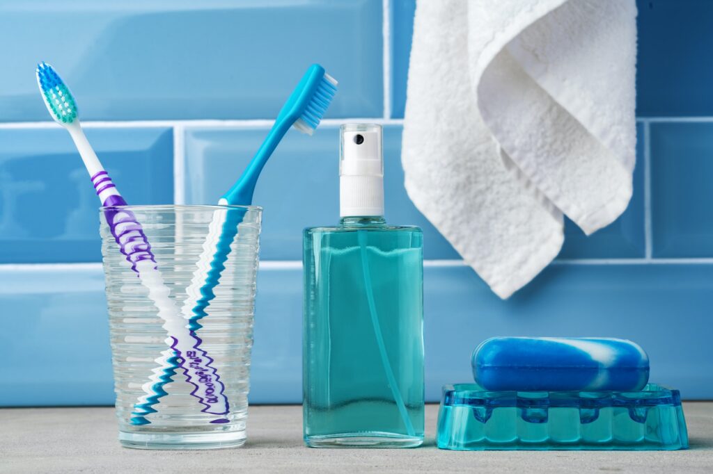 The toothbrushes in a glass in blue bathroom