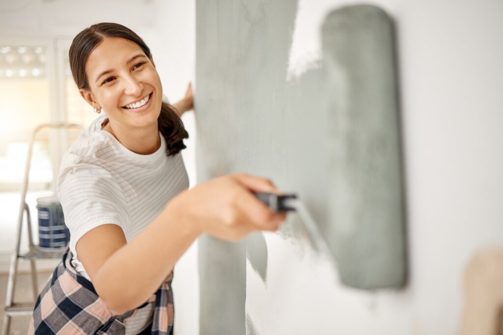 Theres nothing you cant do yourself. Shot of a beautiful young woman painting a wall at home.
