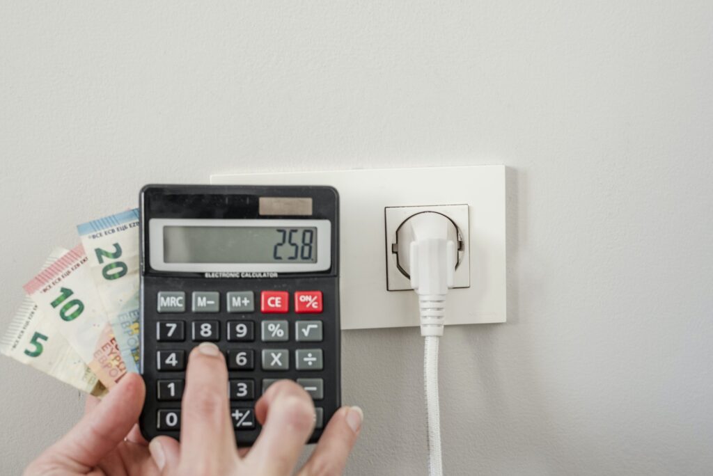 Euro banknotes and calculator next to the electric plug- concept of electricity cost increase